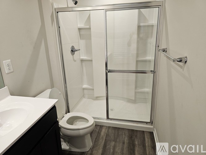 A white toilet is in a bathroom with a walk-in shower.