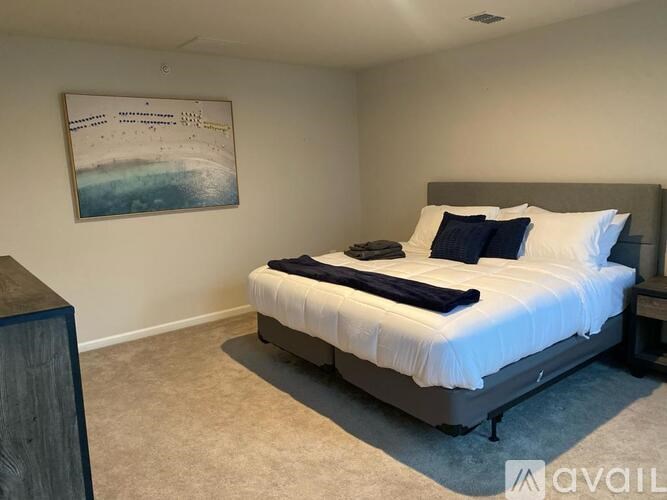 A bedroom with a bed, pillows, and a picture on the wall.
