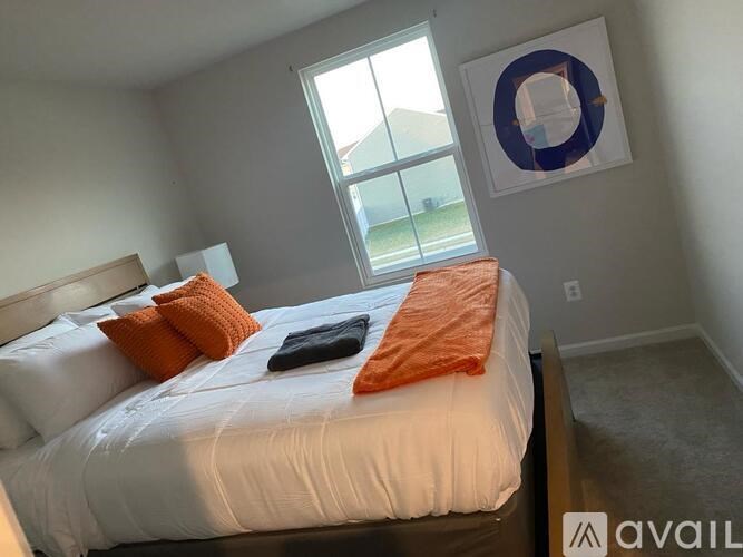 A bedroom with a white bed and orange pillows.