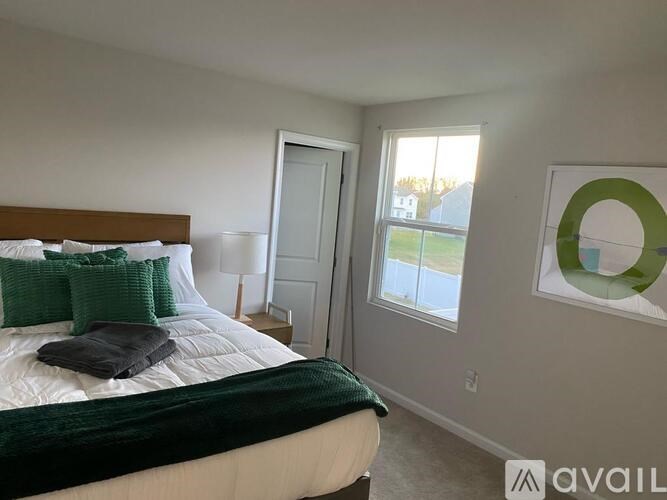 A bedroom with a bed, pillows, and a window.