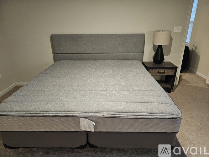 A bed with a grey headboard and a grey mattress is in a room.