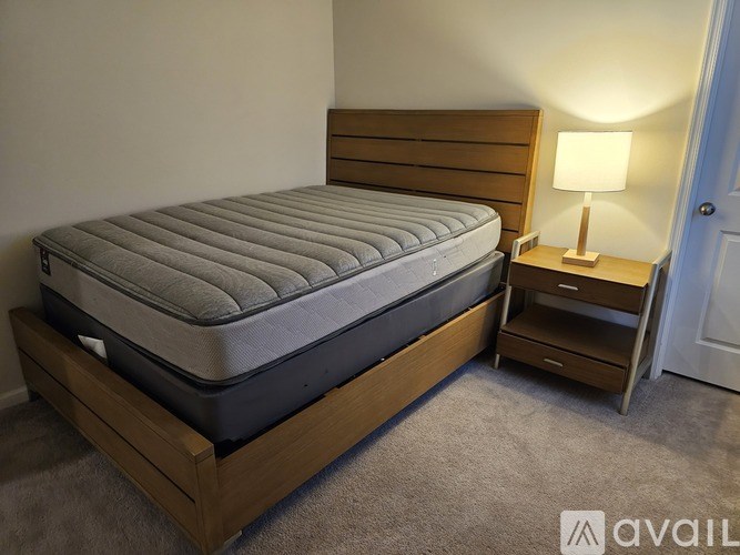 A bed with a wooden headboard and footboard sits in a room with a grey carpet.
