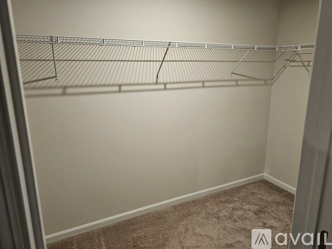 Empty room with a carpeted floor and a metal shelf.