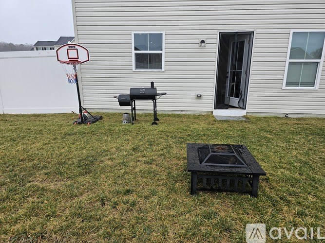 A basketball hoop stands in a grassy yard next to a house.