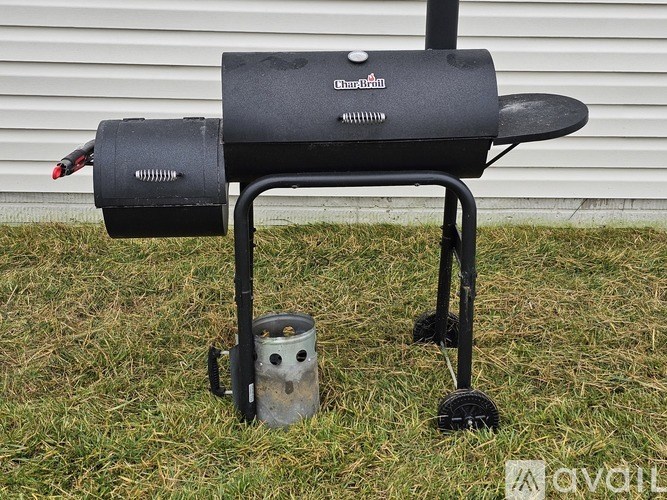 A charcoal grill is placed on a grassy area.