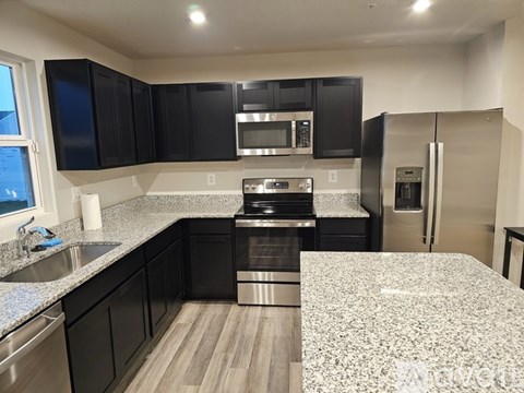 A kitchen with black cabinets and stainless steel appliances.