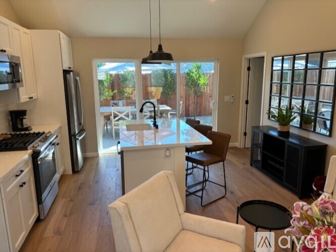 A modern kitchen with white appliances and a dining area with a table and chairs.