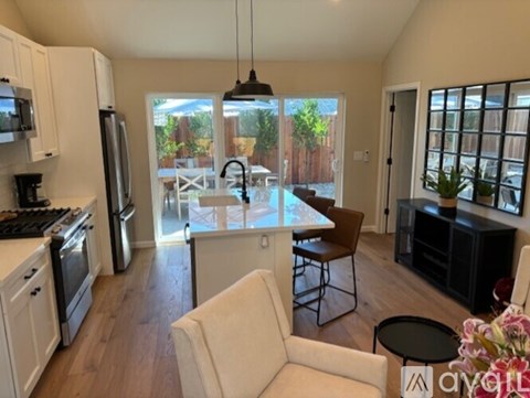 A modern kitchen with white appliances and a dining area with a table and chairs.
