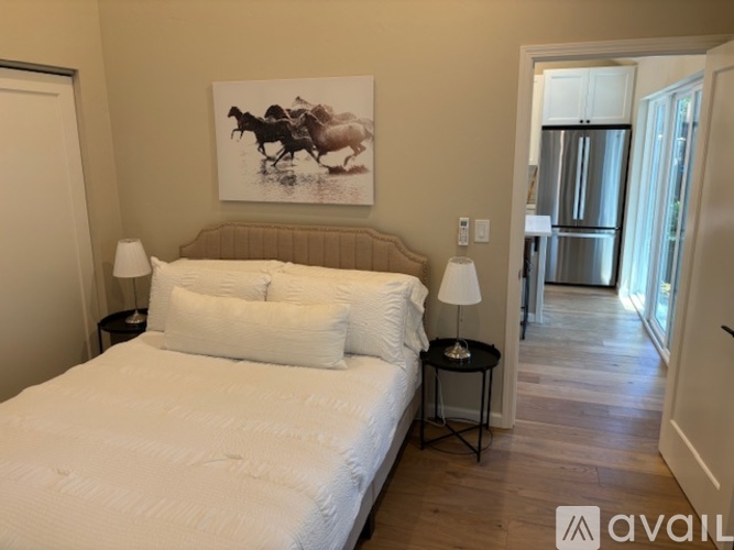 A bedroom with a large bed and a painting of a horse and rider on the wall.