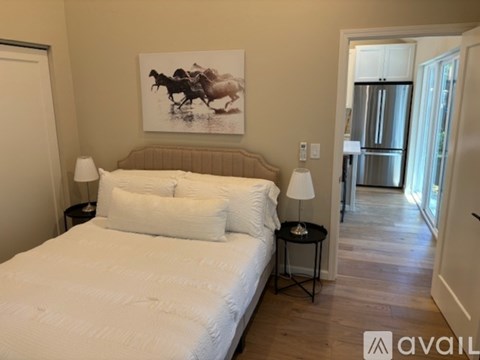 A bedroom with a large bed and a painting of a horse and rider on the wall.