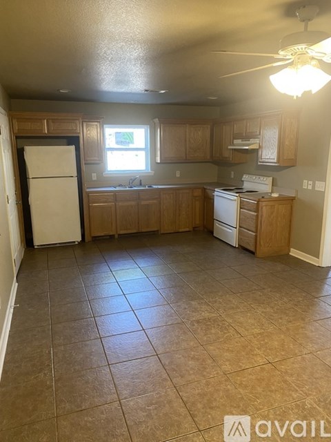 A kitchen with brown tile floors and wooden cabinets.