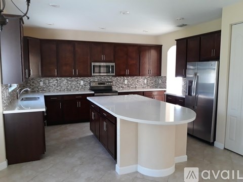 A kitchen with brown cabinets and a stone backsplash.