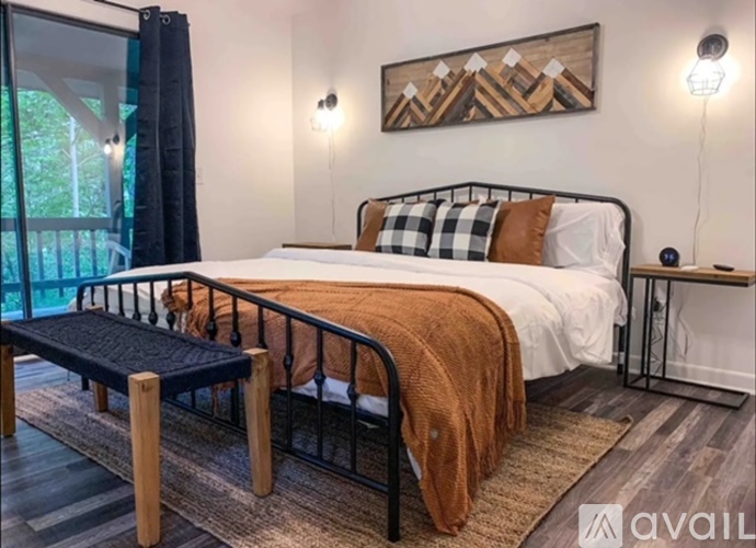 A bedroom with a large bed and a window overlooking a balcony.