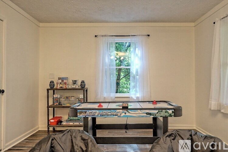 A room with a pool table and a window with white curtains.