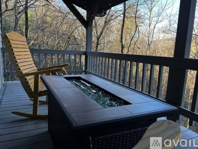 A wooden rocking chair is on a deck next to a hot tub.