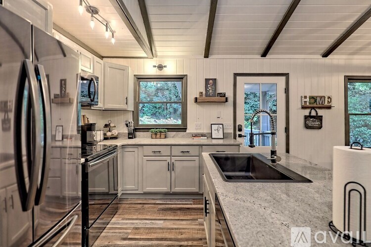 A kitchen with white cabinets and a black fridge.