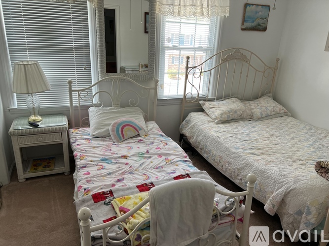 A bedroom with two beds, one with a rainbow design on the pillow.