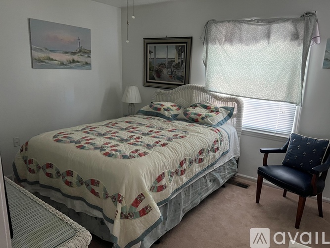 A bedroom with a bed, chair, and pictures on the wall.