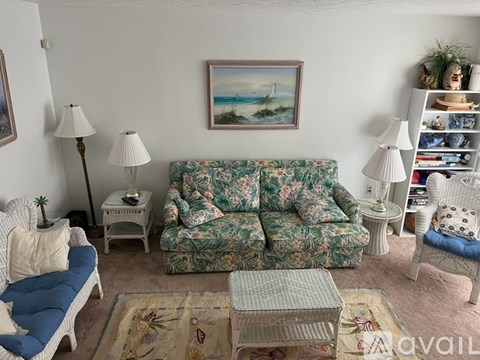 A living room with a floral sofa and a painting on the wall.