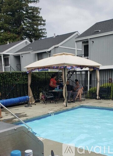 A poolside area with people sitting under a canopy.