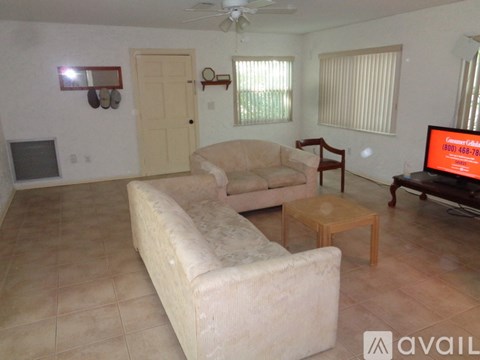 A living room with a couch, chair, and television displaying a phone number.