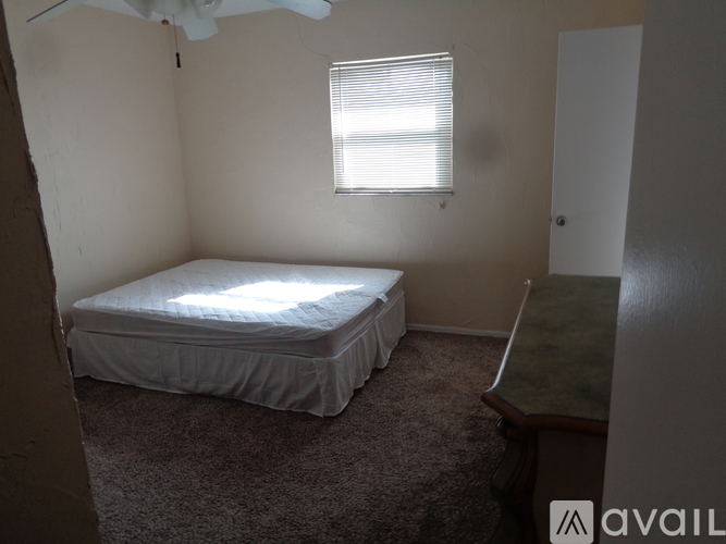 A bedroom with a bed, window, and a carpeted floor.