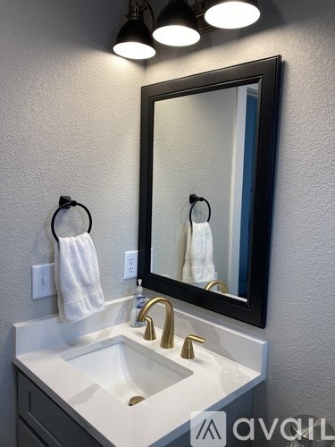 A bathroom sink with a gold faucet and a mirror above it.