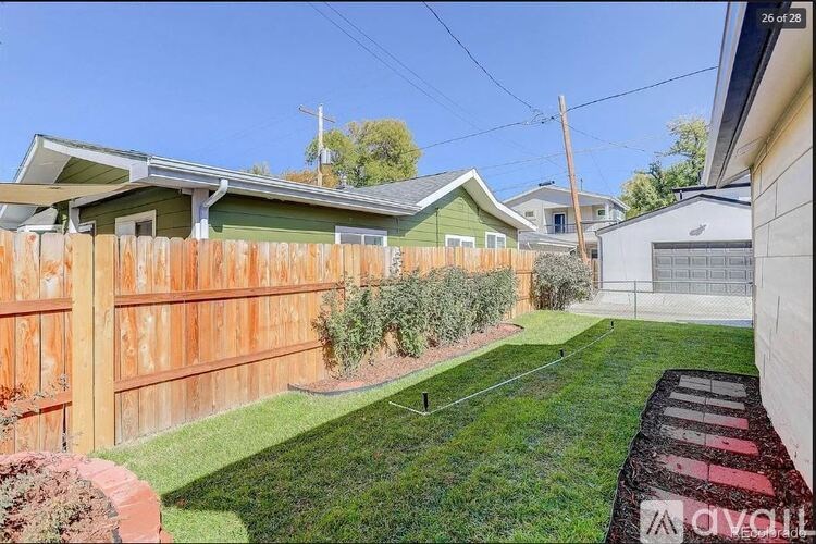 A backyard with a wooden fence and a green lawn.