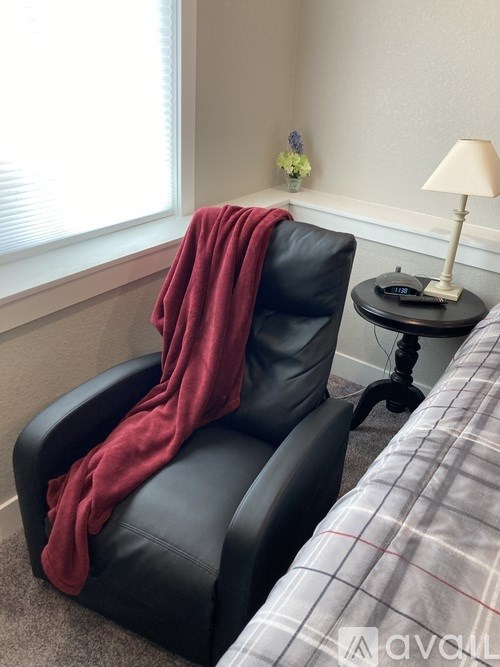 A red blanket is draped over a black leather chair.