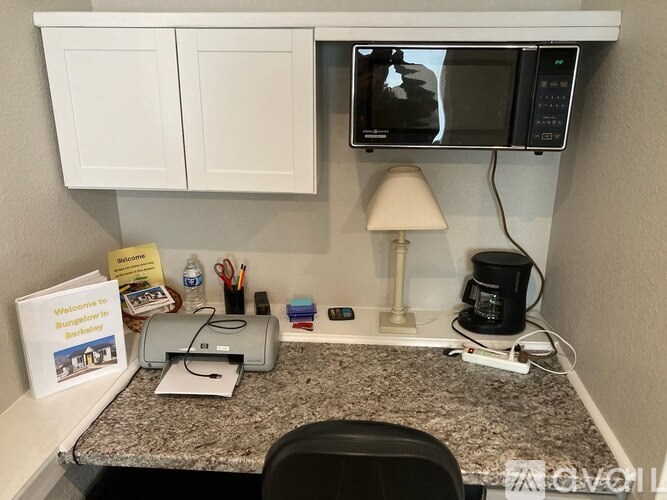 A small office space with a desk, chair, and a microwave above it.