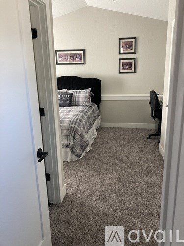 A bedroom with a bed, chair, and pictures on the wall.