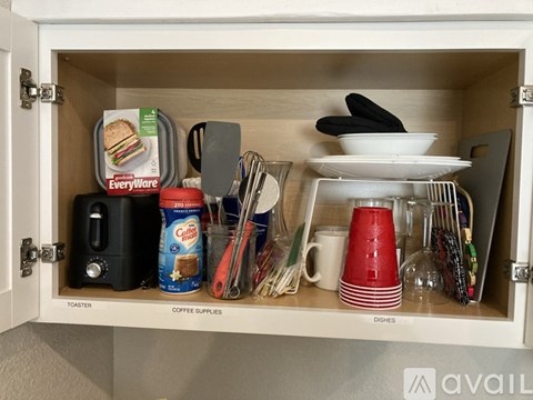 A kitchen cabinet drawer with toaster, coffee supplies, and dishes.