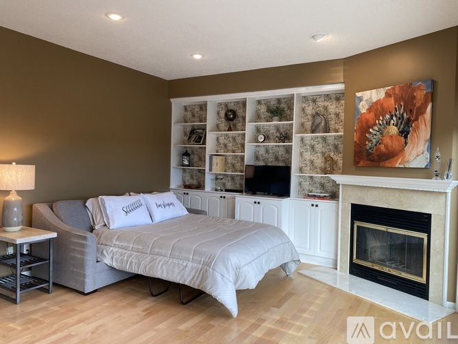 A bedroom with a grey bed and a fireplace.