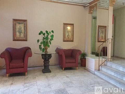 A living room with two red chairs and a table with a plant on it.