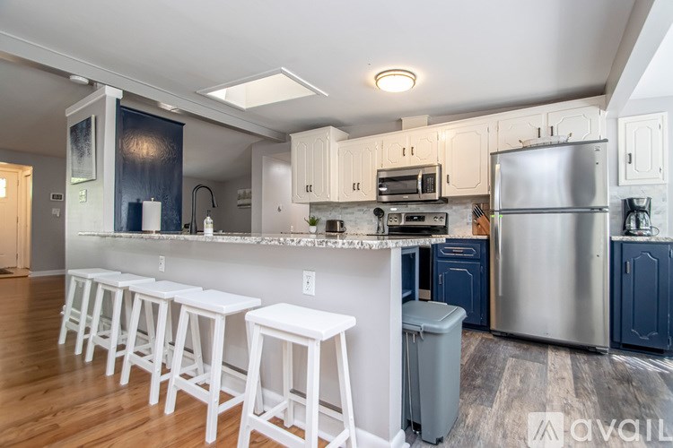 A kitchen with white stools and a bar area.
