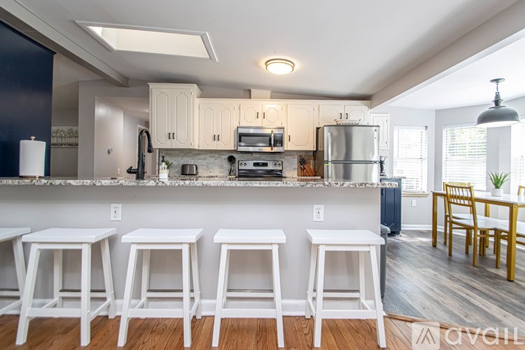 A kitchen with white stools and a bar area.