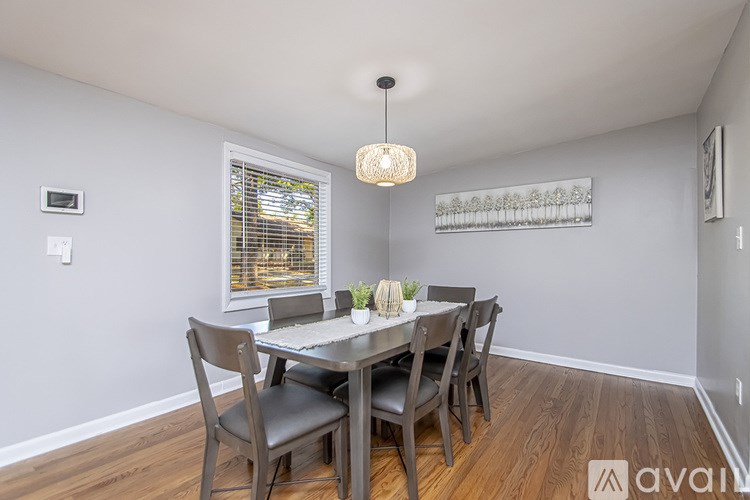 A dining room with a table set for two and chairs around it.