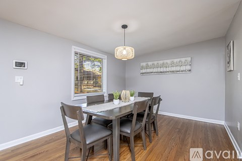 A dining room with a table set for two and chairs around it.