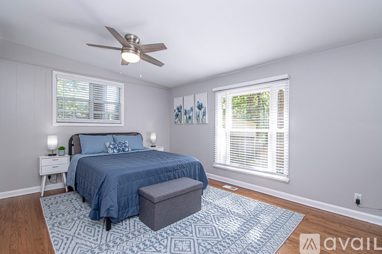 A bedroom with a bed, a bench, and a ceiling fan.