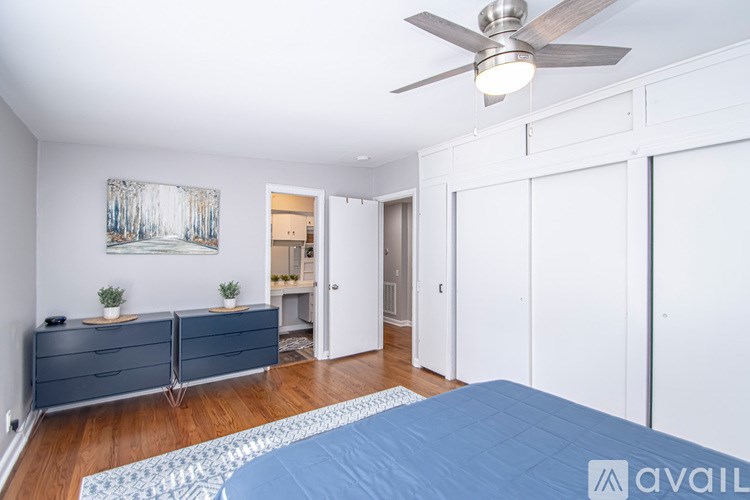 A bedroom with a blue bedspread and a ceiling fan.