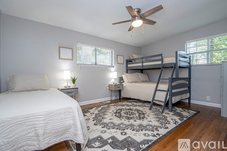 A bedroom with a white bed, a rug, and a ceiling fan.