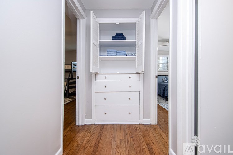 A white closet with drawers and shelves is open to a hallway.