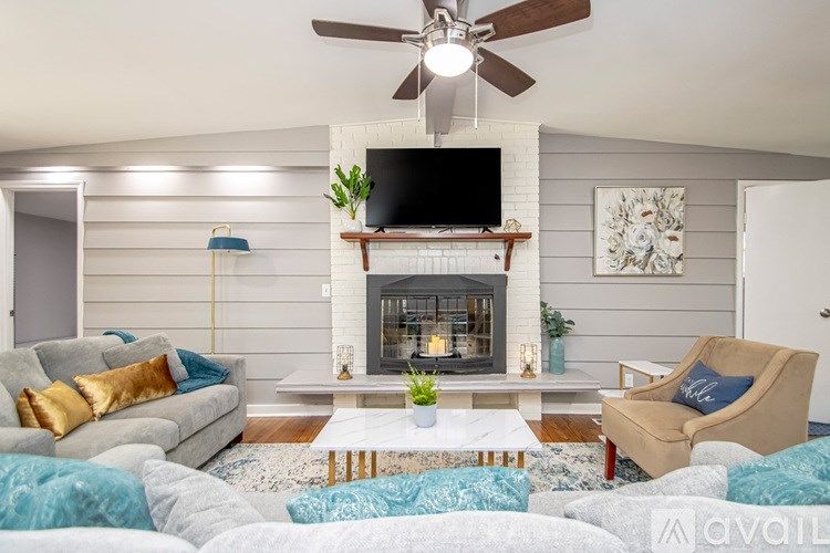 A living room with a fireplace and a television mounted above it.