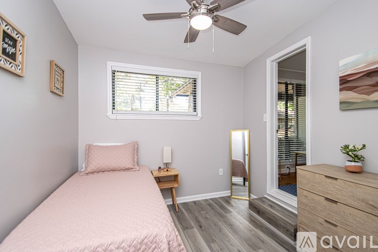 A bedroom with a pink bedspread and a ceiling fan.