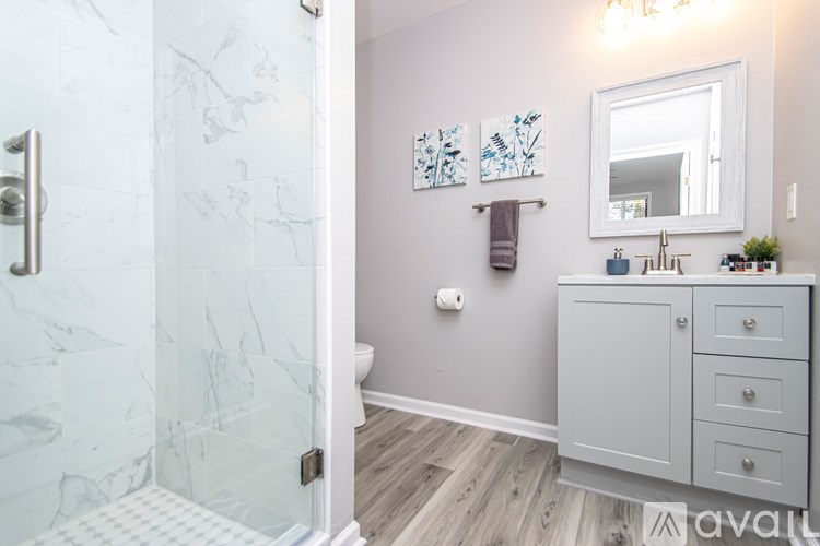 A bathroom with a marble shower and a grey cabinet.