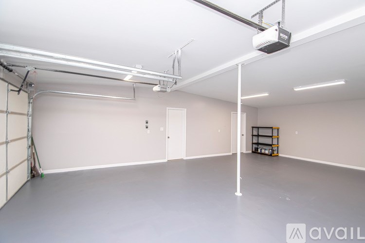 A spacious room with a grey floor and white walls, featuring a white pillar, a white ceiling, and a white door.