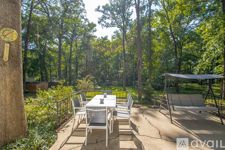 A patio with a table and chairs is surrounded by trees.
