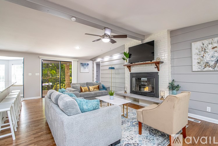 A living room with a grey couch, a white chair, a fireplace, and a television.
