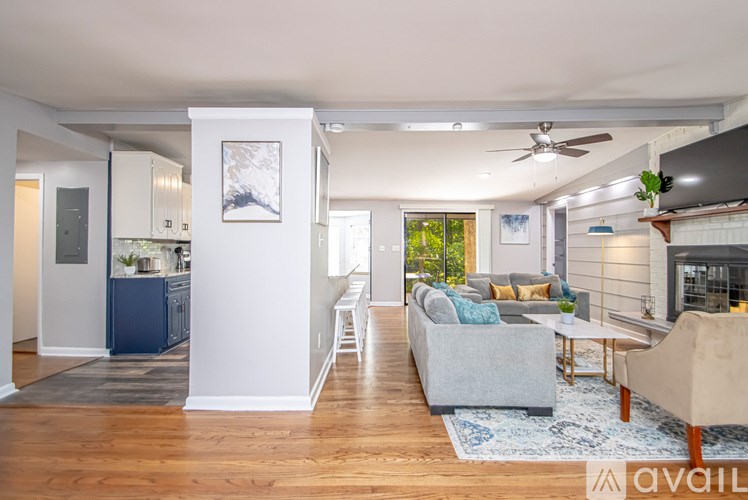 A spacious living room with a grey sofa and a white wall.