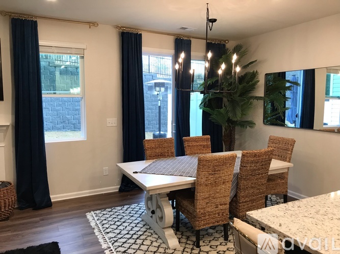 A dining room with a white table and brown chairs.